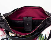 Close-up of a black leather bag with a floral patterned lining.