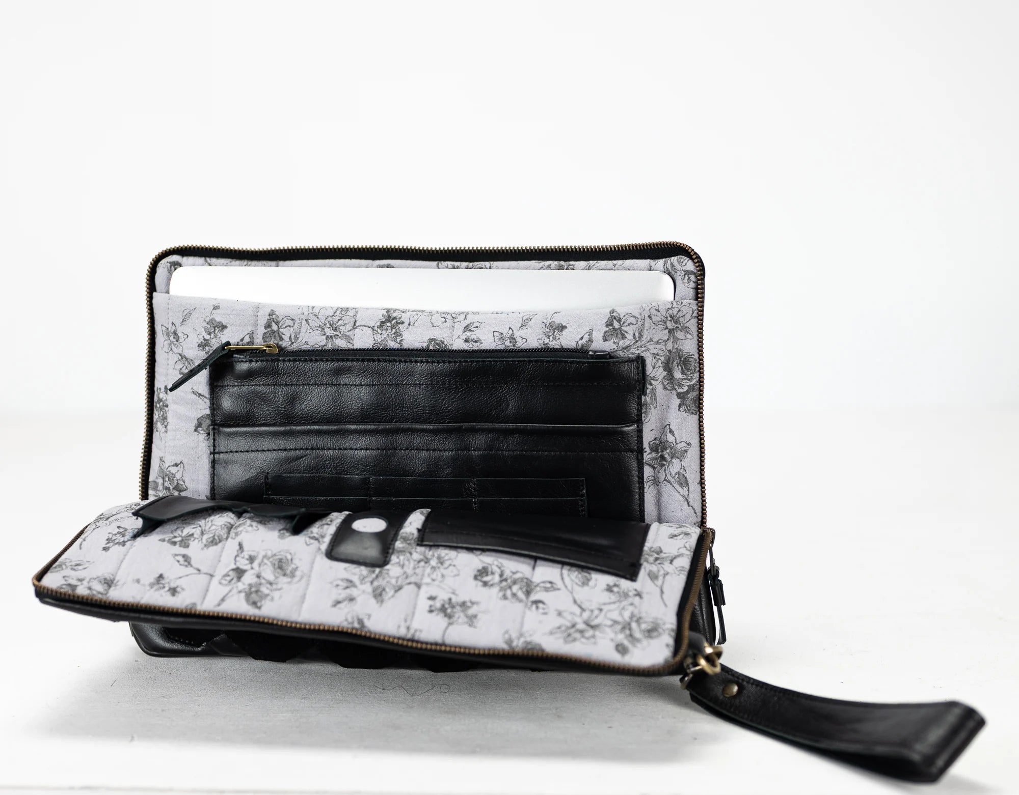 Floral-patterned clutch bag with a black interior on a white background