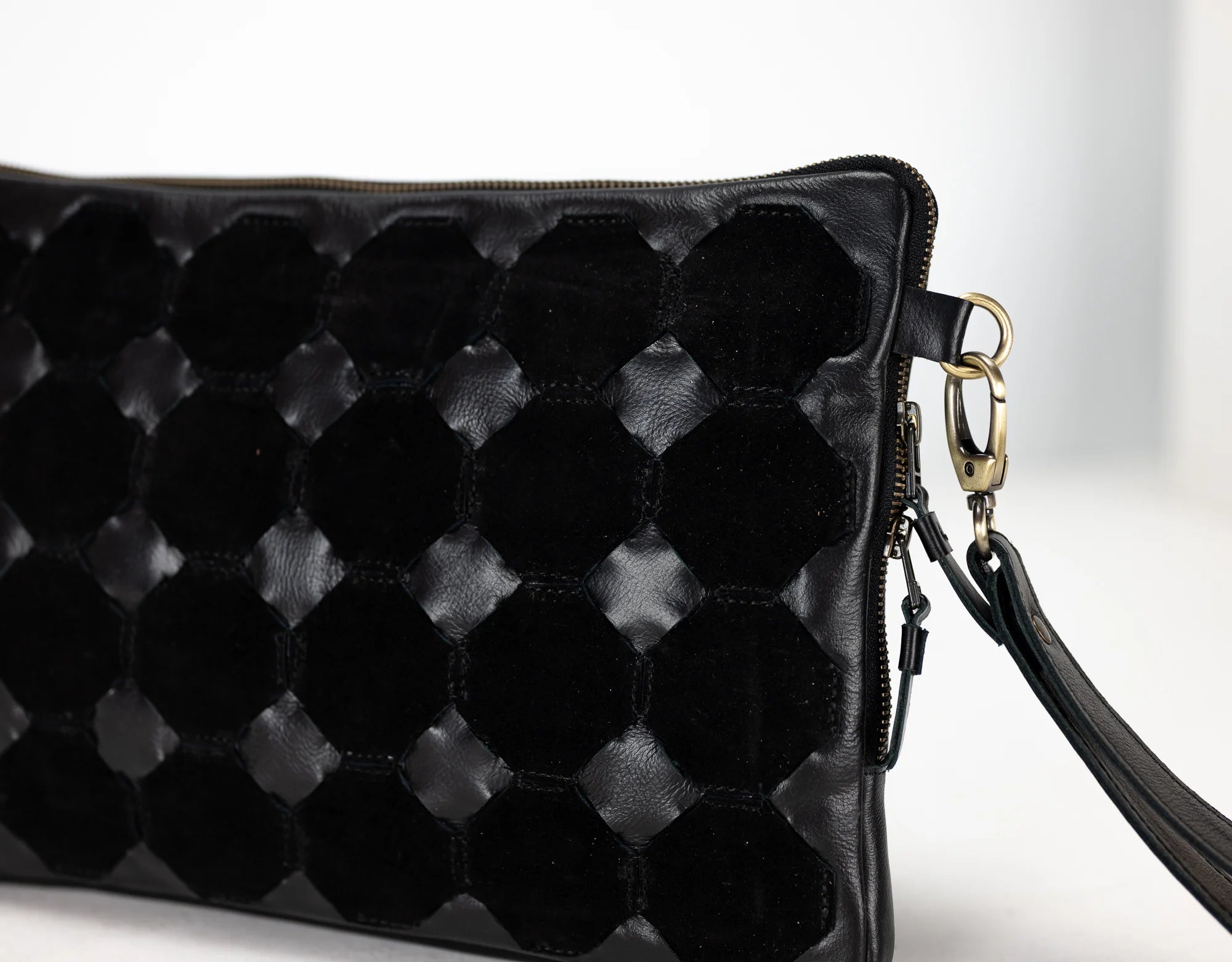 Black quilted handbag with a strap on a light background