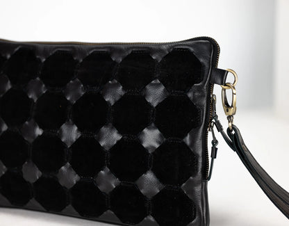 Black quilted handbag with a strap on a light background
