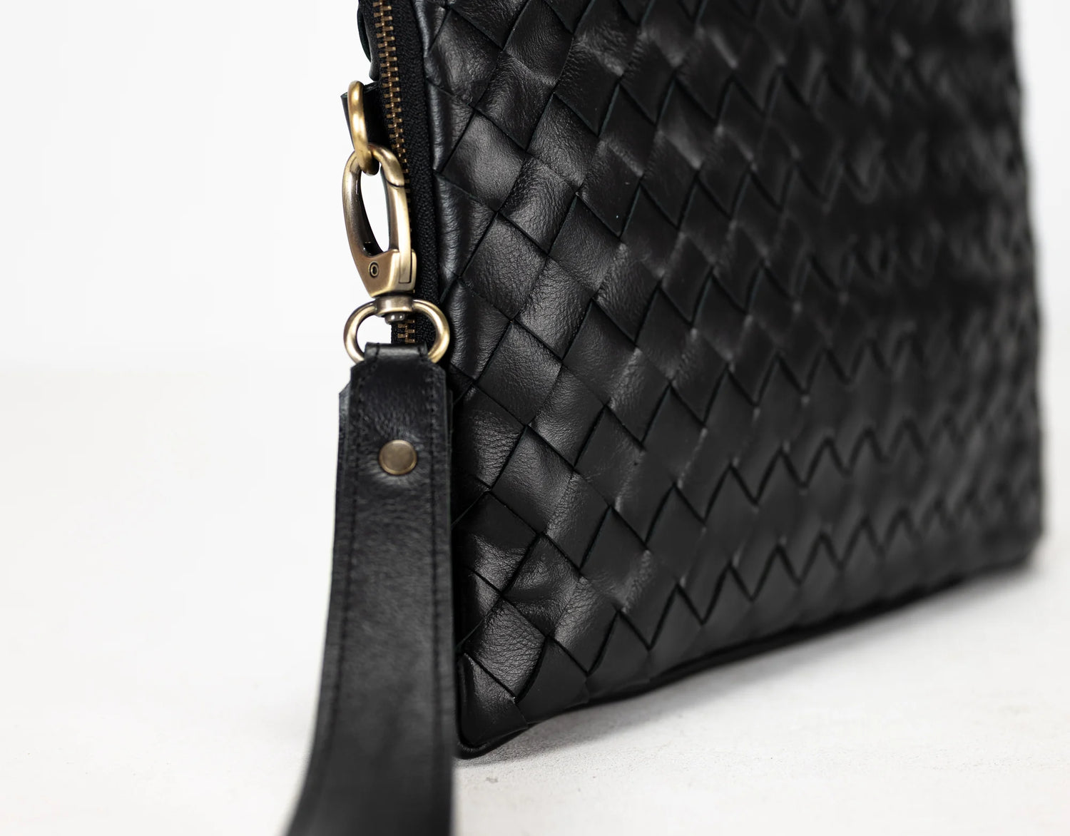 Black woven leather clutch bag with gold zipper on a white background