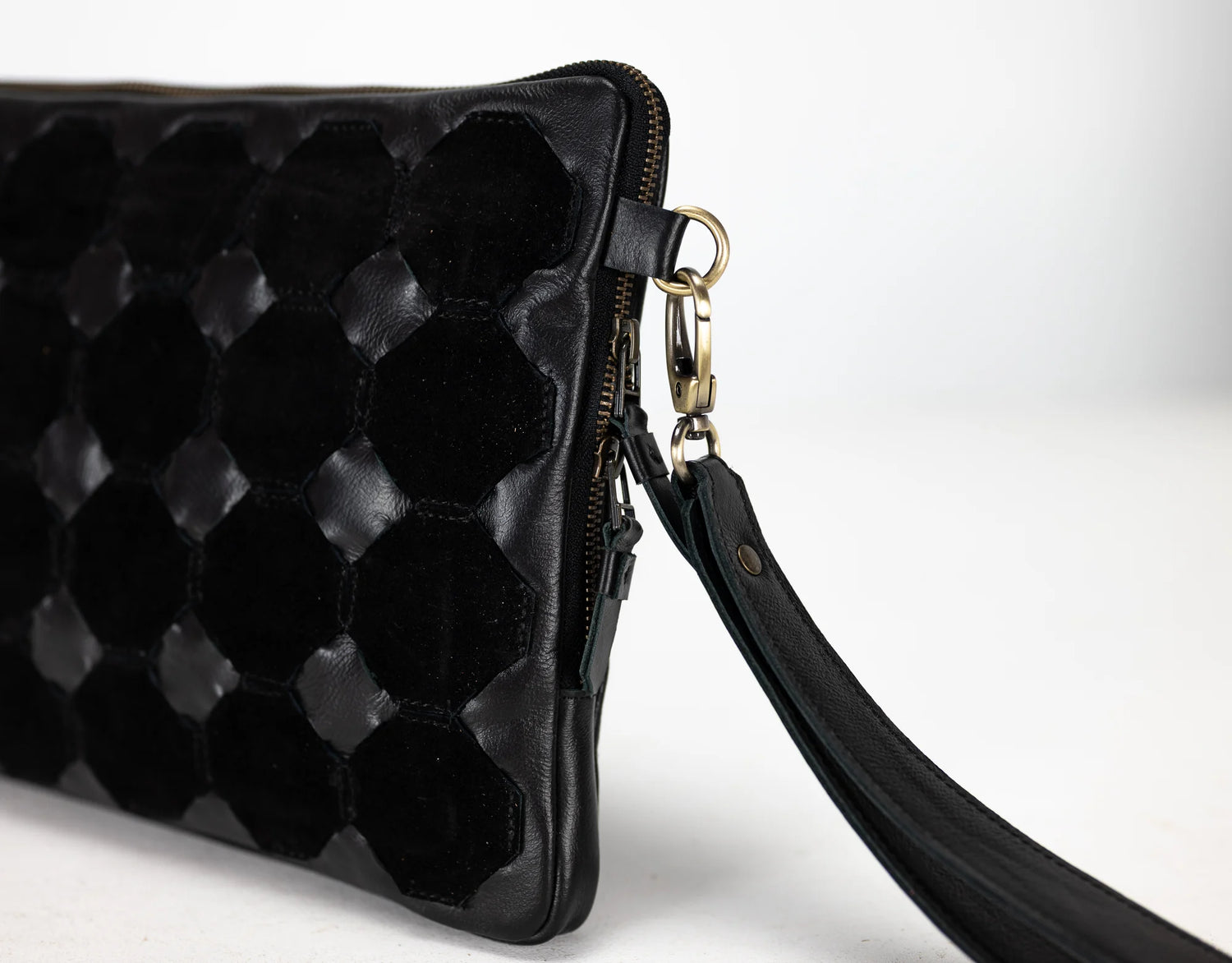 Black quilted clutch bag with a strap on a white background
