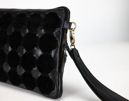 Black quilted clutch bag with a strap on a white background