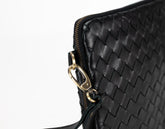 Black woven handbag with gold clasp on a white background