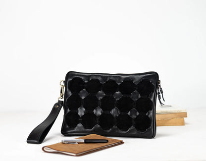 Black quilted clutch bag with a strap on a white background