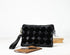 Black quilted clutch bag with a strap on a white background