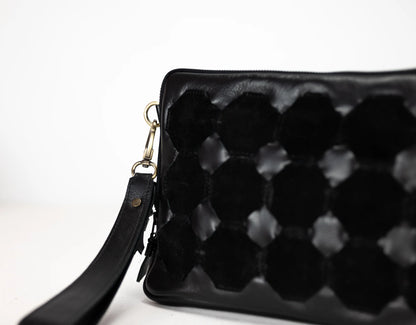 Black textured clutch bag with a strap on a white background