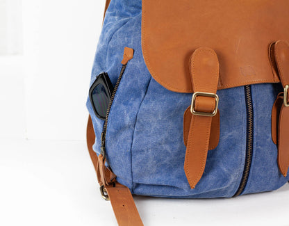 Blue backpack with brown leather straps and accents on a white background