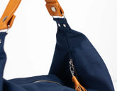 Navy blue bag with brown leather strap on a white background