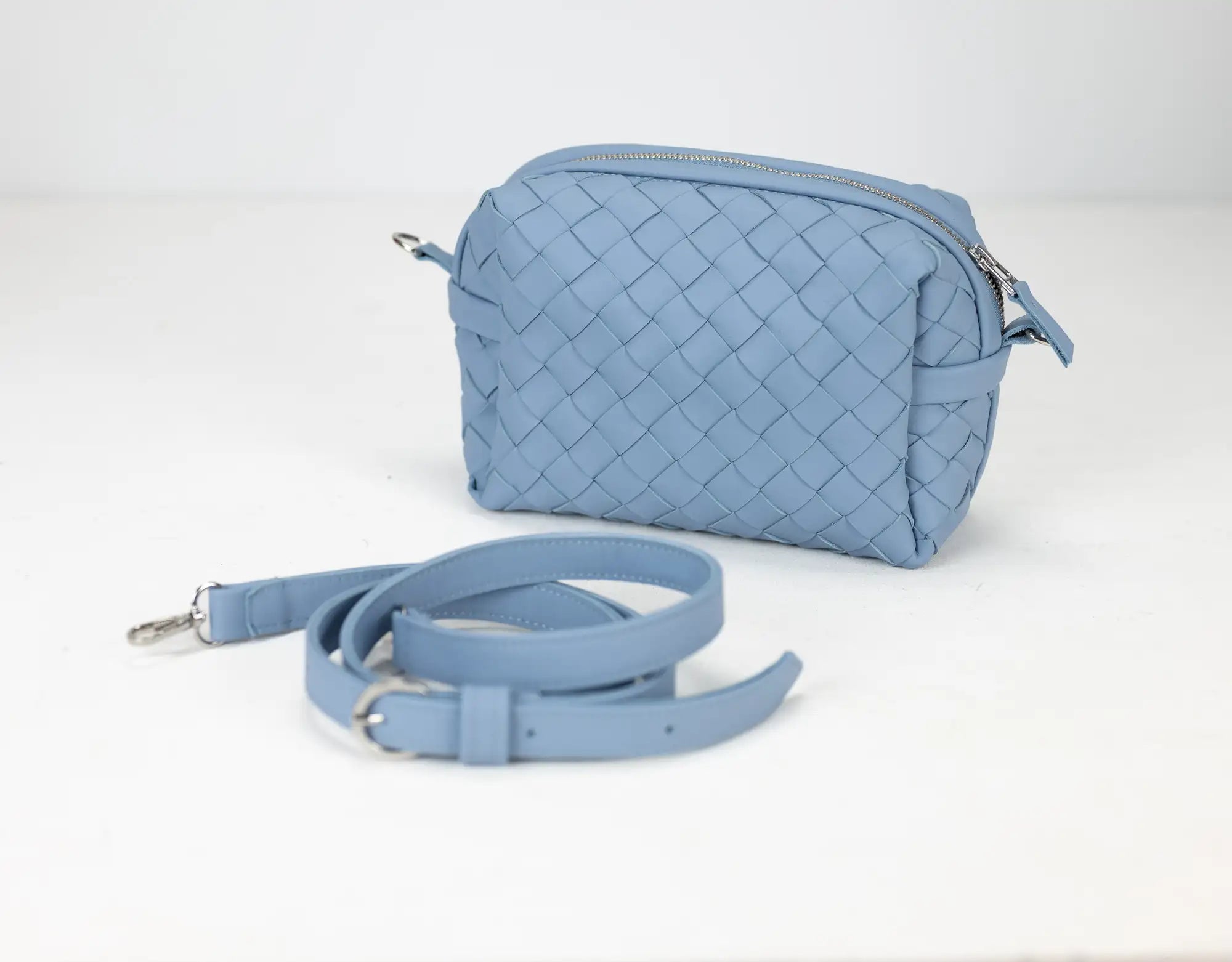 Light blue woven handbag with a matching strap on a white background