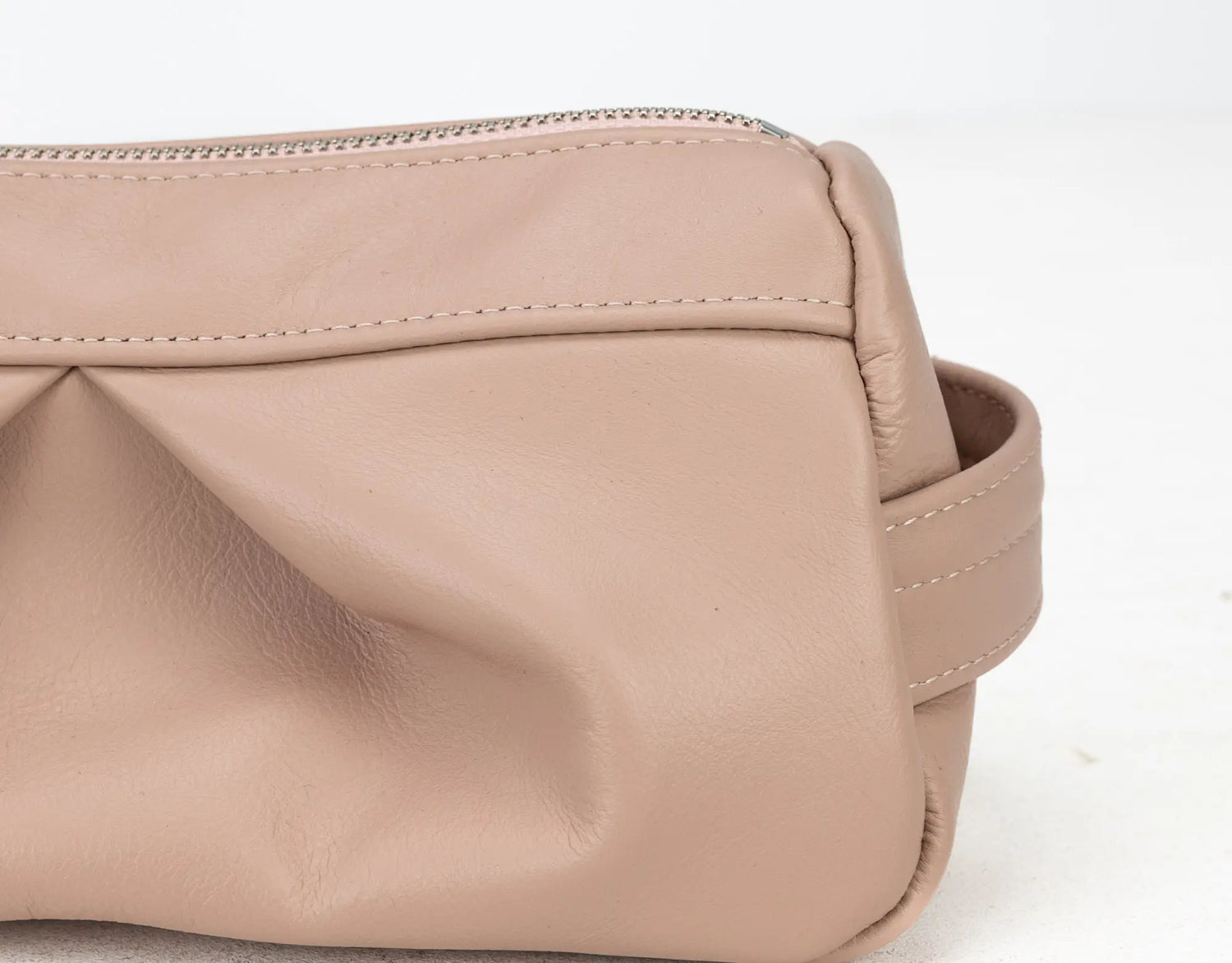 Beige leather bag with a strap on a white background