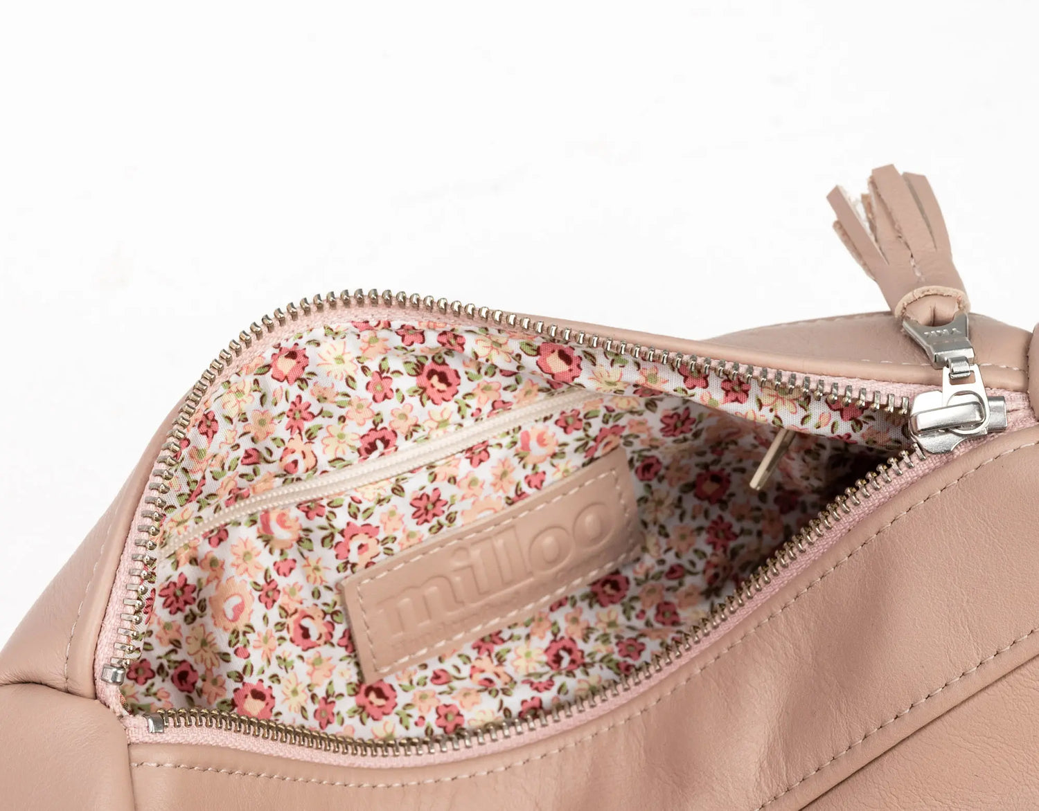 Close-up of a beige handbag with floral interior pocket on a white background