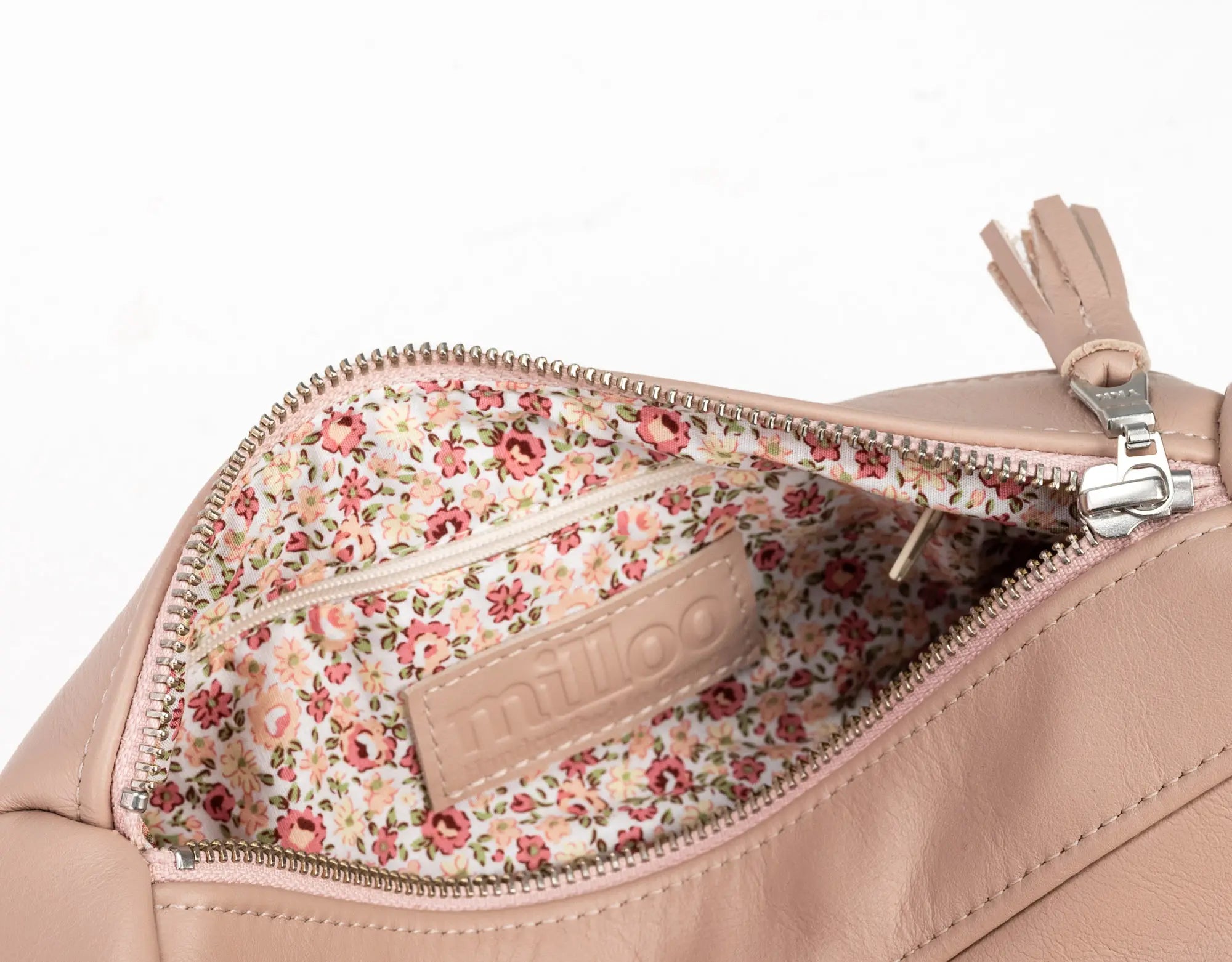 Close-up of a beige handbag with floral interior pocket on a white background