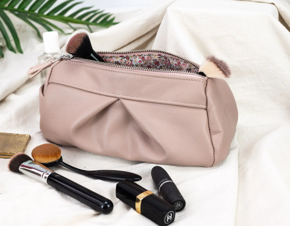 Makeup bag with brushes and lipsticks on a light background
