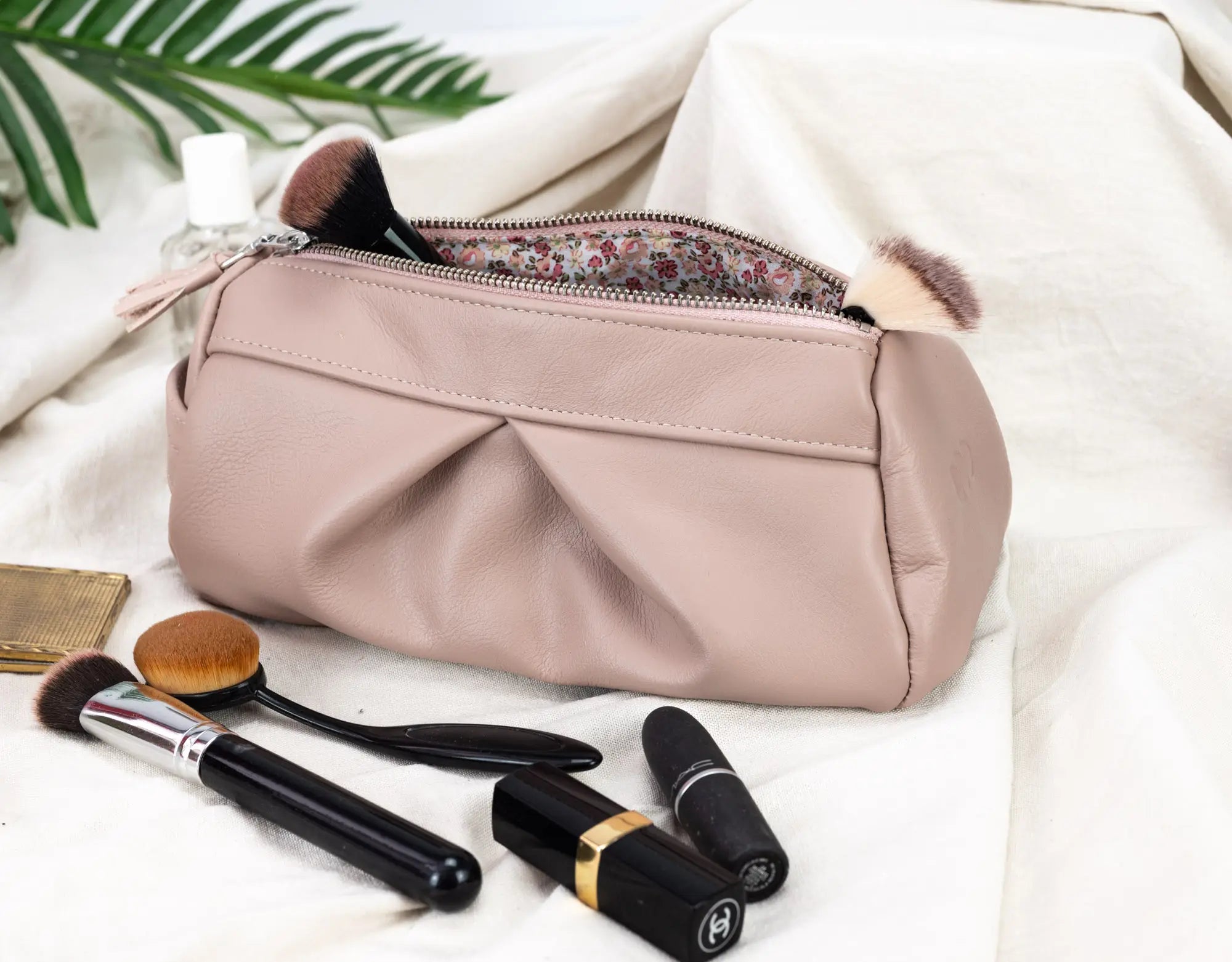 Makeup bag with brushes and lipsticks on a light background
