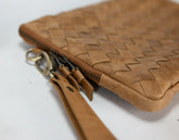 Brown woven leather clutch with keychain on a white background