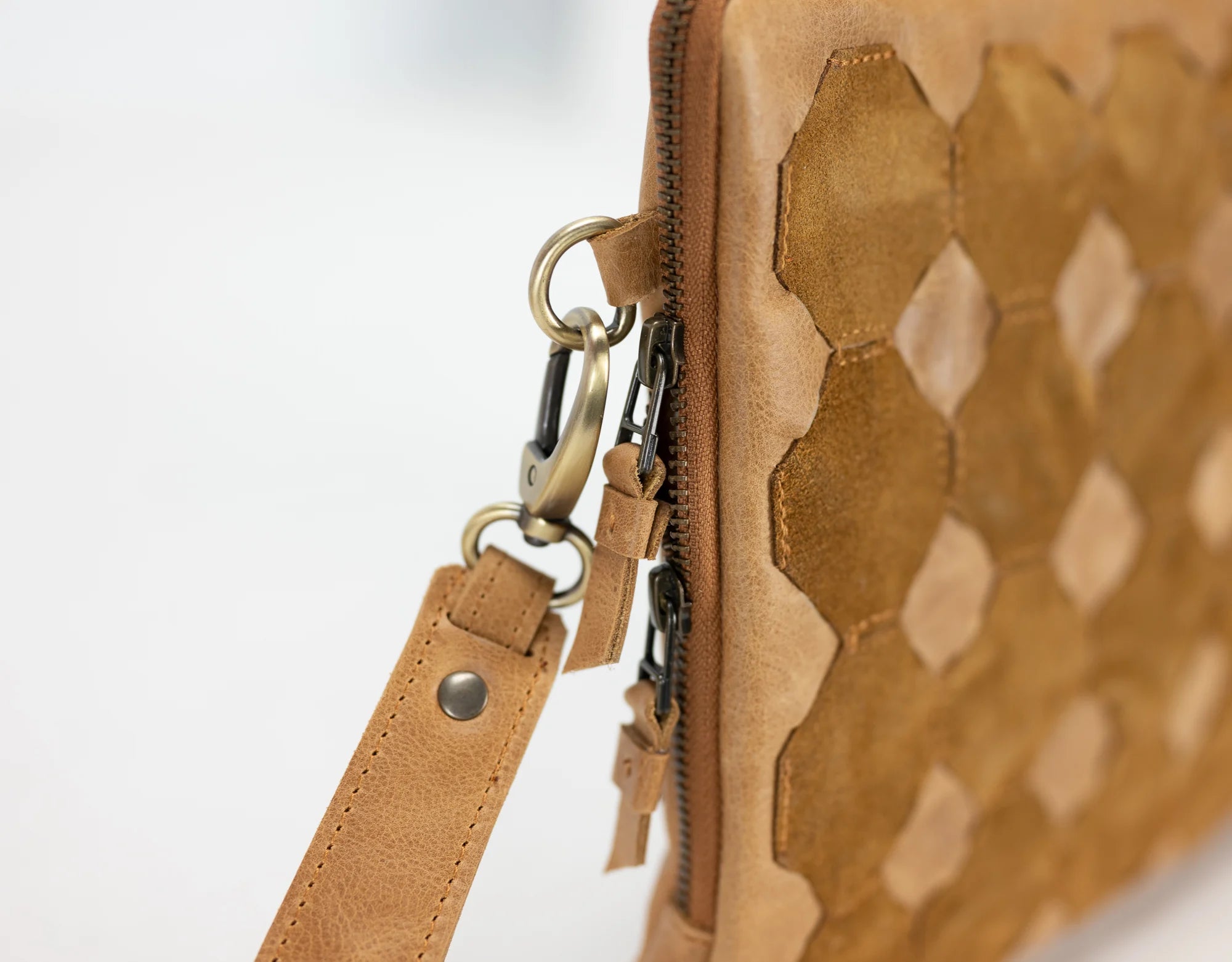 Close-up of a brown leather bag with geometric pattern on a white background