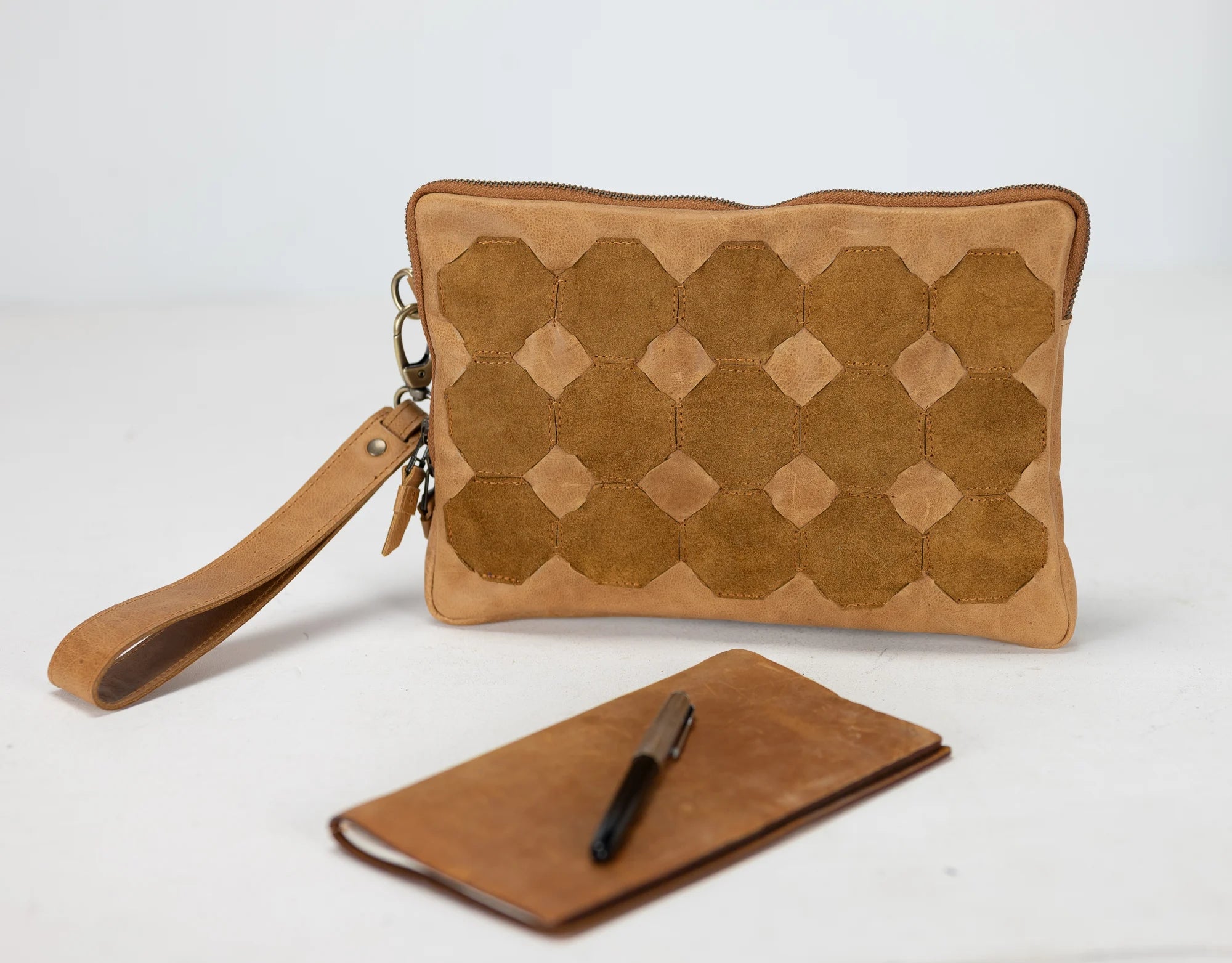 Brown leather clutch with geometric pattern and matching wallet on a white background