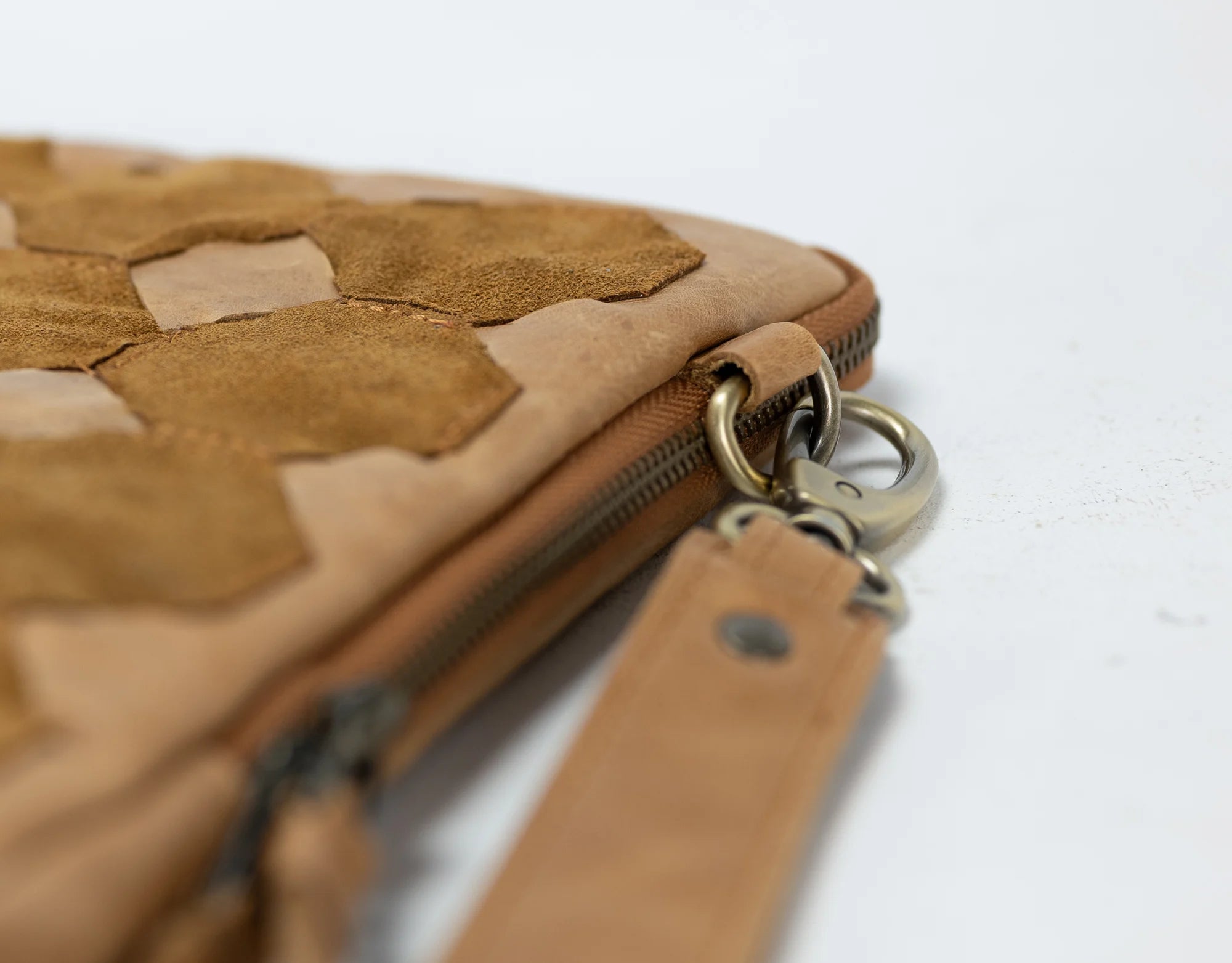 Close-up of a brown leather clutch with a zipper on a white background