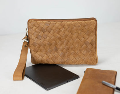 Brown woven leather clutch with a strap, placed on a white surface.