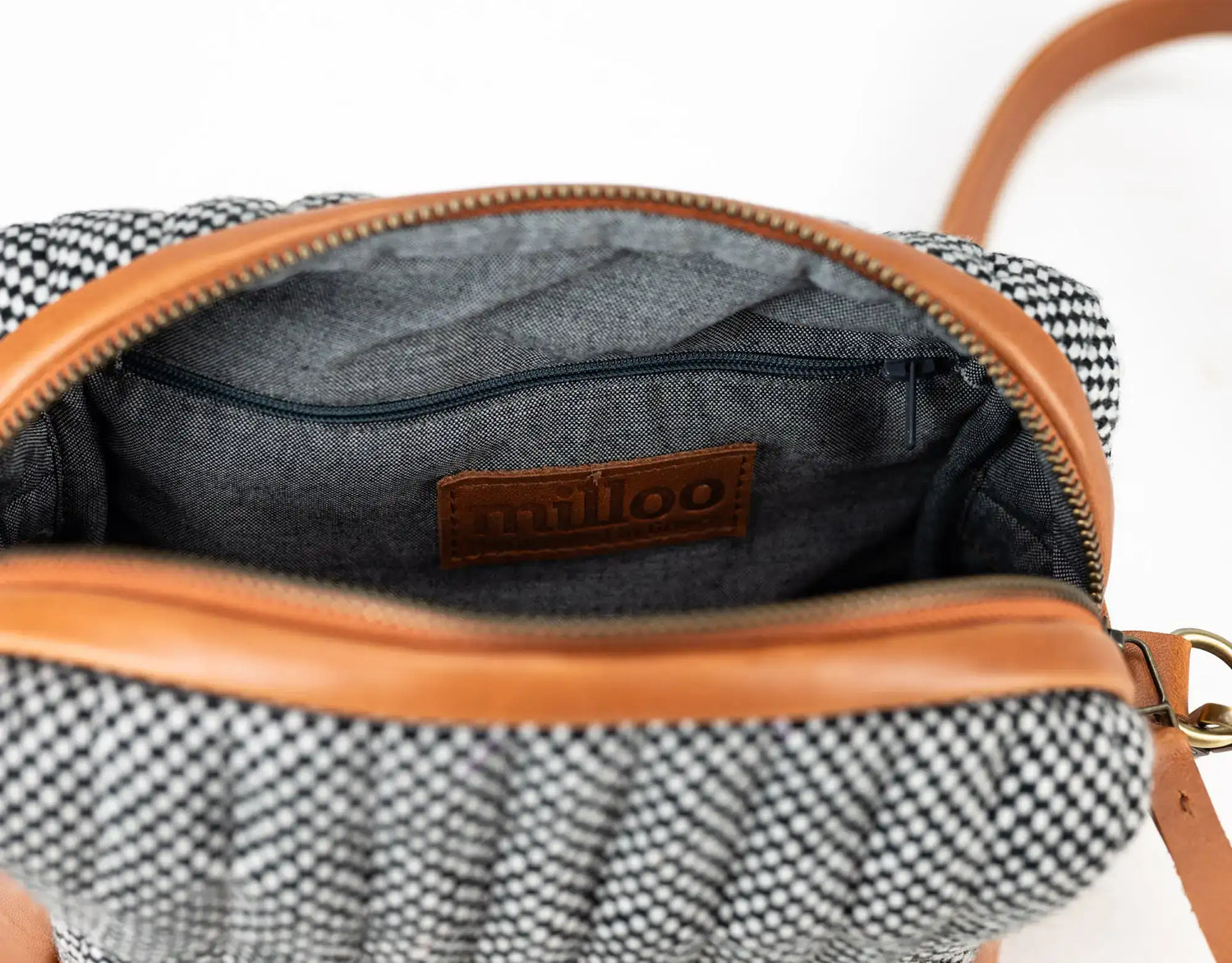 Open handbag with checkered pattern and brown leather trim, featuring a brand logo.