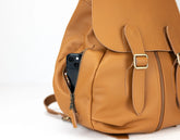 Brown leather backpack with a phone in a pocket on a white background