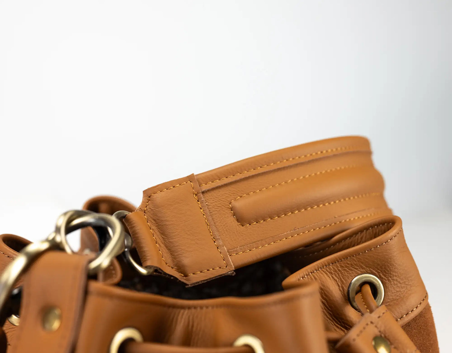 Close-up of a brown leather bag with a strap on a white background