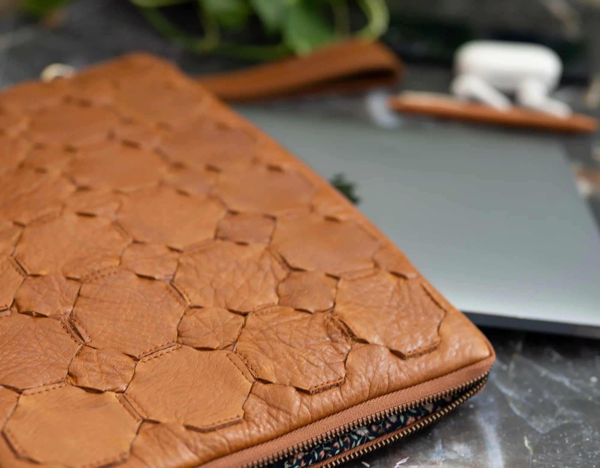 Brown leather clutch with floral pattern on a dark surface