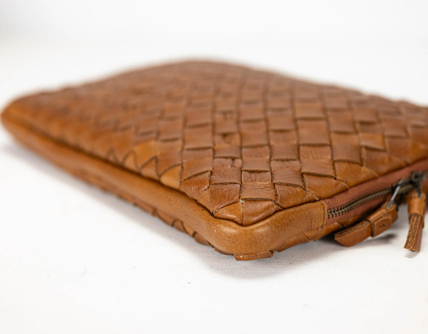 Brown woven leather clutch bag on a white background