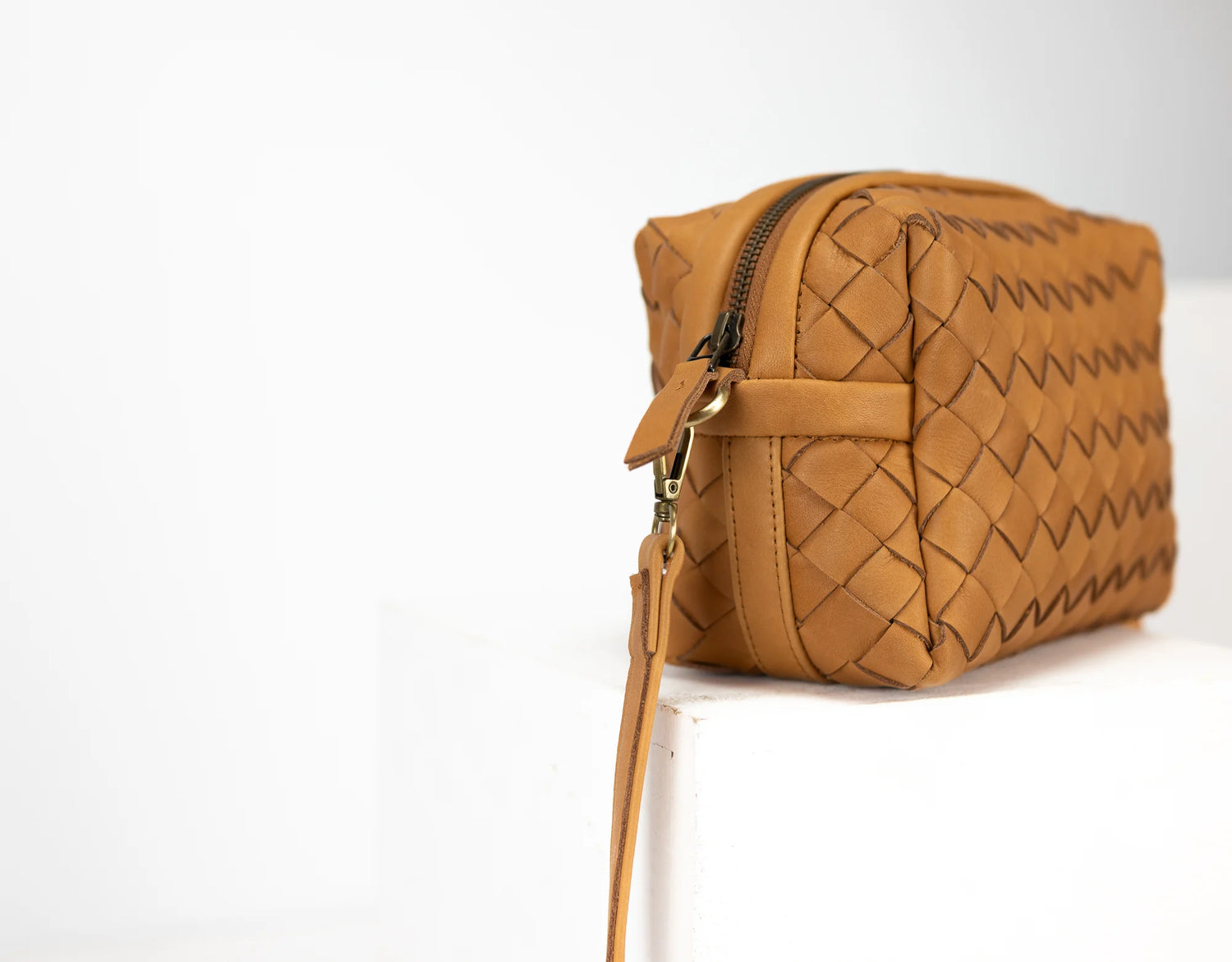 Brown woven handbag with a strap on a white background