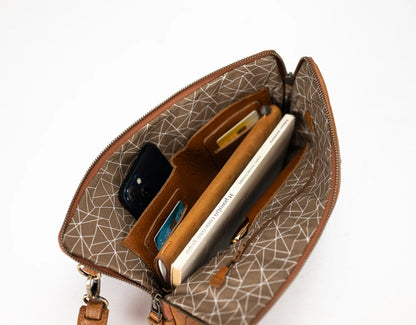 Open brown handbag with geometric pattern, containing a phone and wallet on a white background