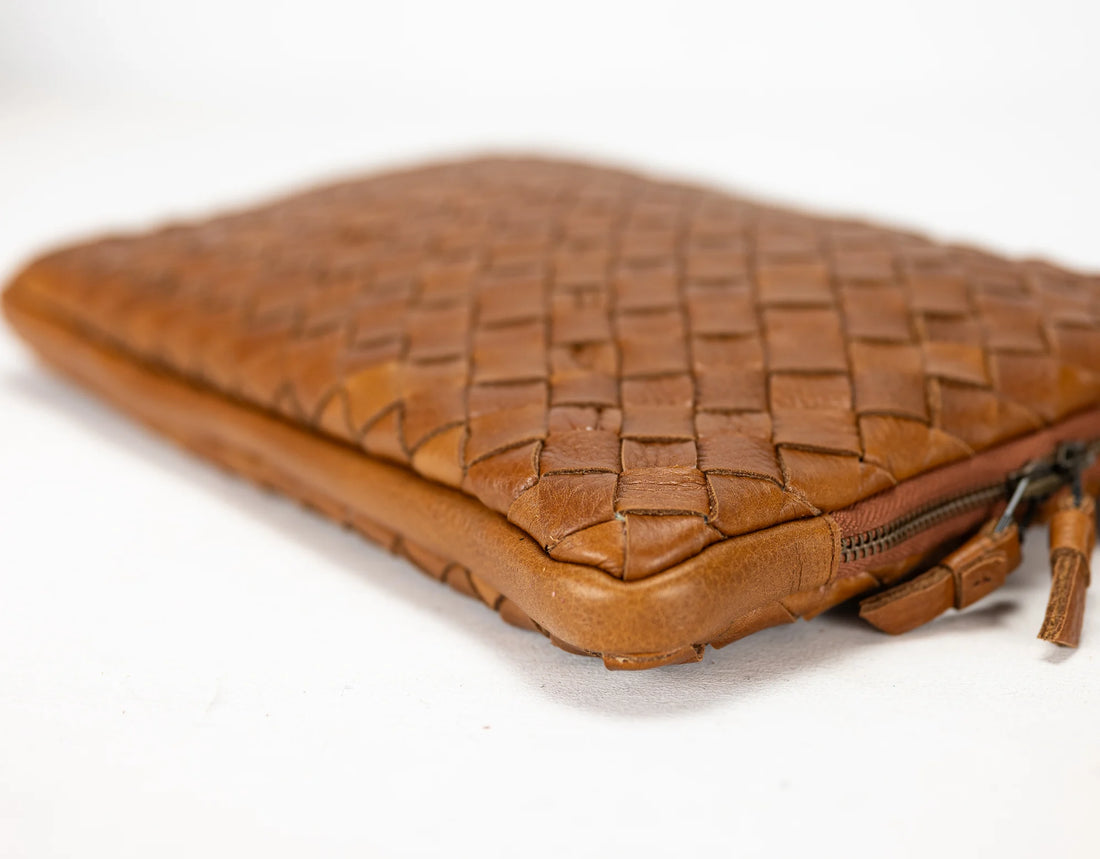 Brown woven leather clutch bag on a white background