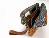 Open brown leather clutch with floral interior on a white background