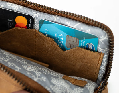 Brown leather wallet with floral pattern holding a card and a Mastercard.