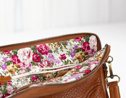 Brown leather handbag with floral interior lining on a white background