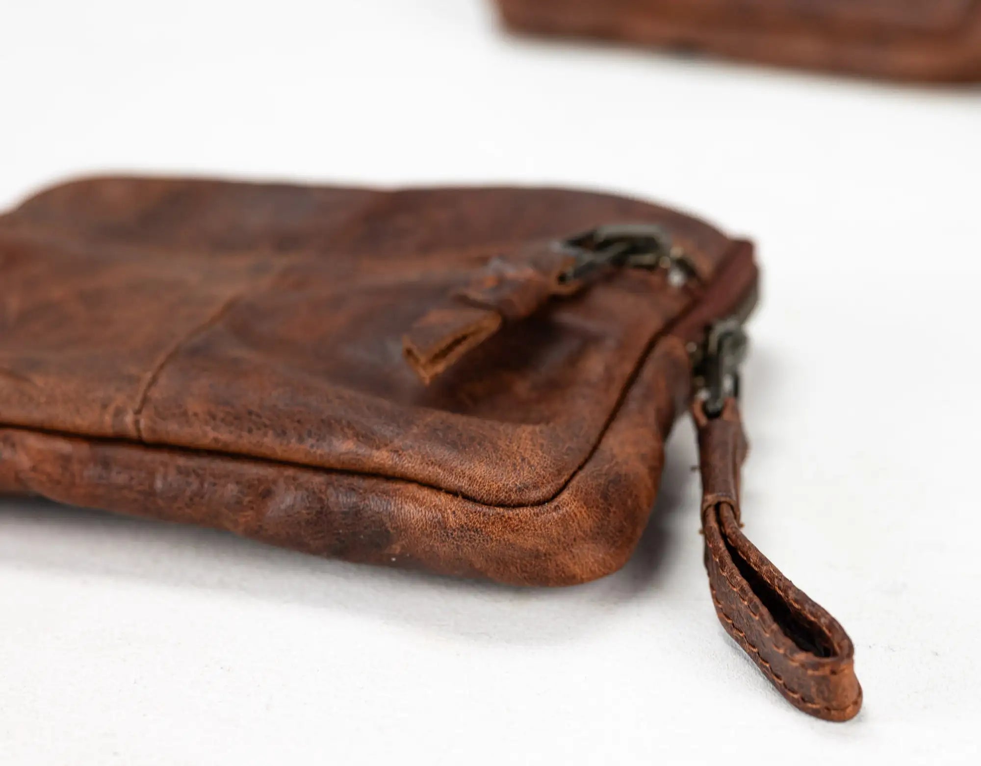 Brown leather pouch with a zipper on a white background