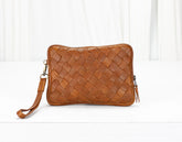 Brown woven leather clutch bag on a white background
