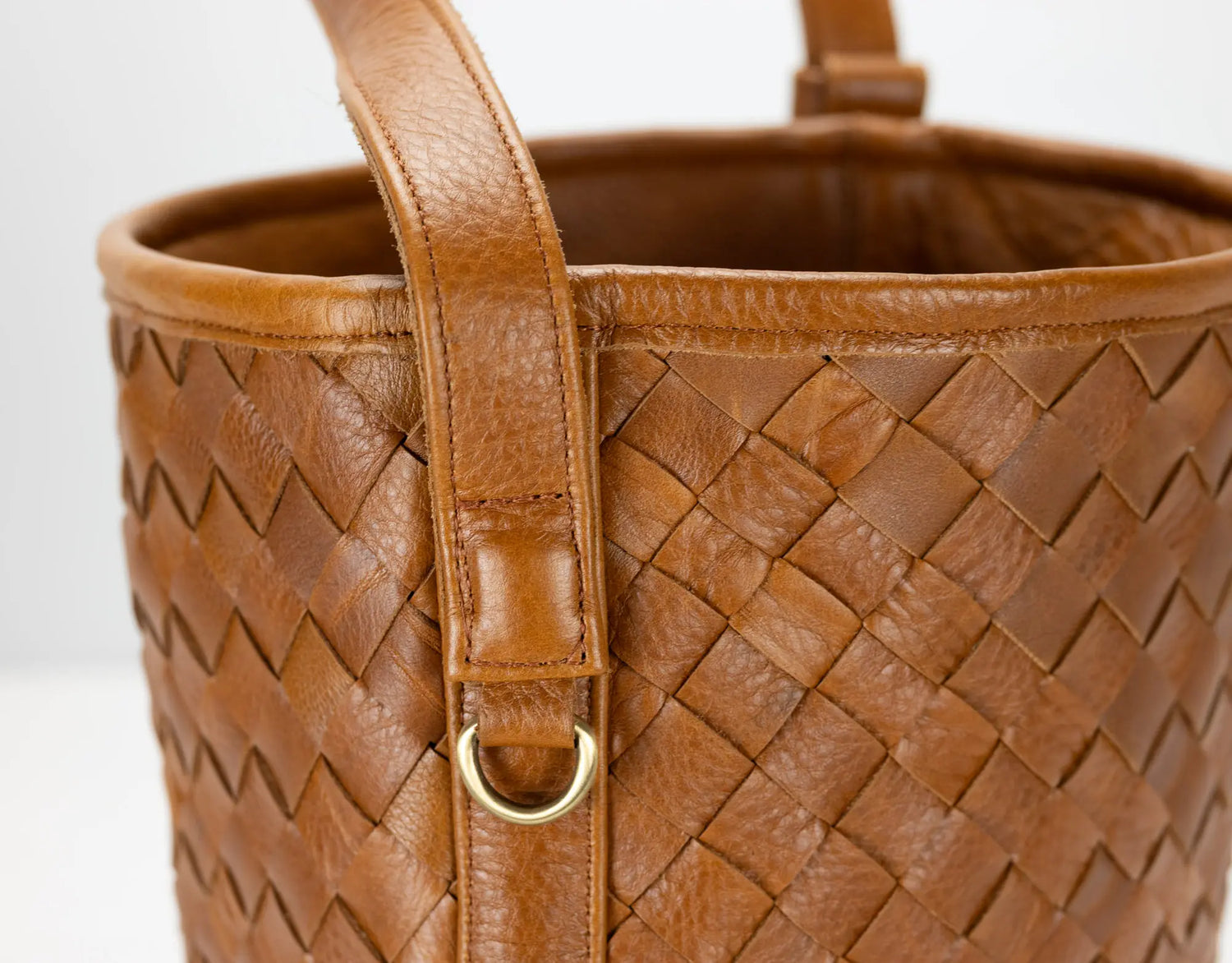 Brown woven leather handbag with a gold clasp on a white background