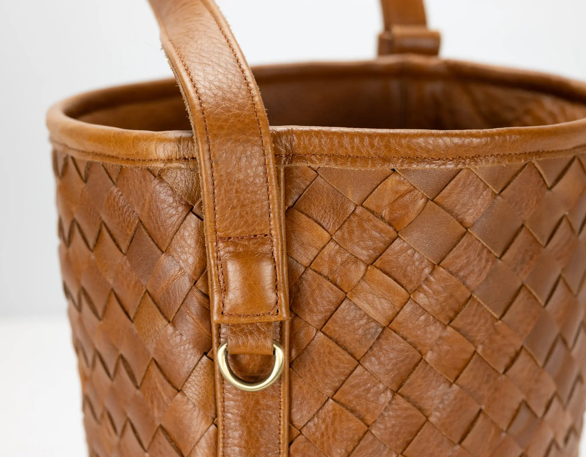 Brown woven leather handbag with a gold clasp on a white background