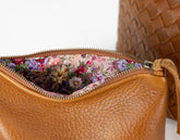 Brown leather bag with floral lining on a white background