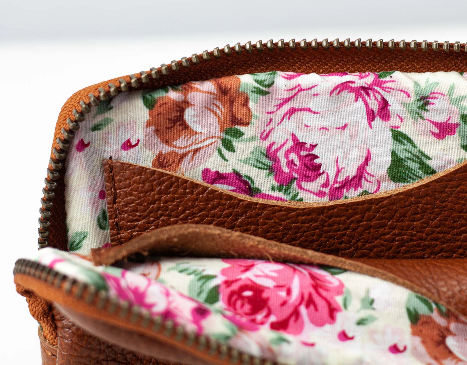 Floral fabric inside a brown leather case with a white background