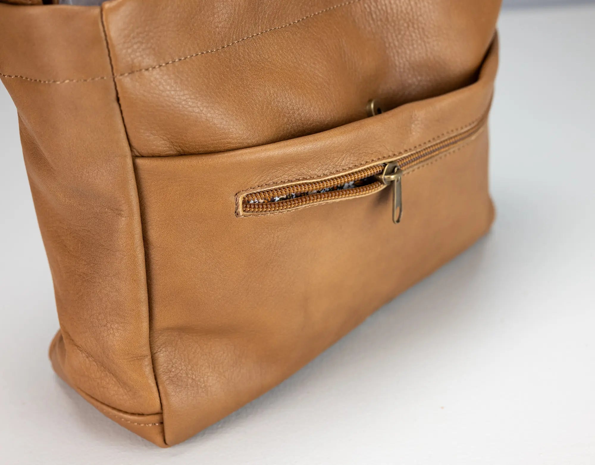 Close-up of a brown leather bag with a zipper on a white background