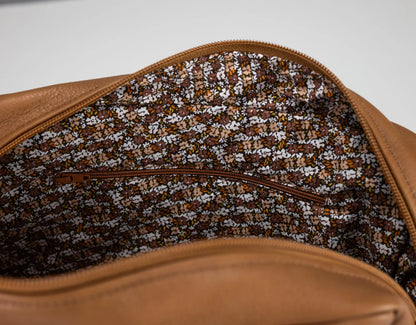 Close-up of a brown leather bag with a patterned interior lining.