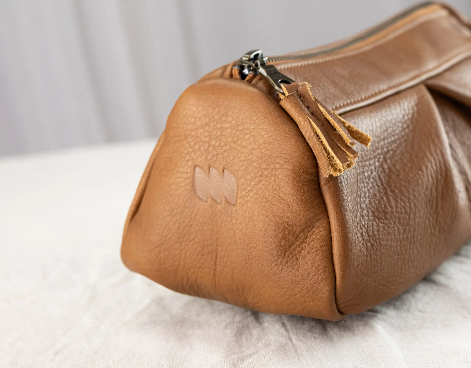 Brown leather bag with a tassel on a light background