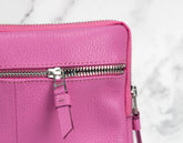 Close-up of a pink leather bag with a zipper on a light gray background