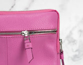Close-up of a pink leather bag with a zipper on a light gray background