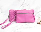 Two pink handbags with a wristlet on a marble surface