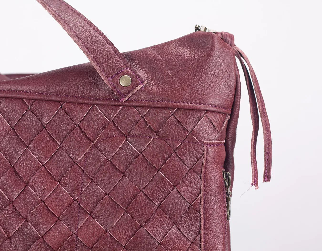 Close-up of a maroon woven leather handbag on a white background