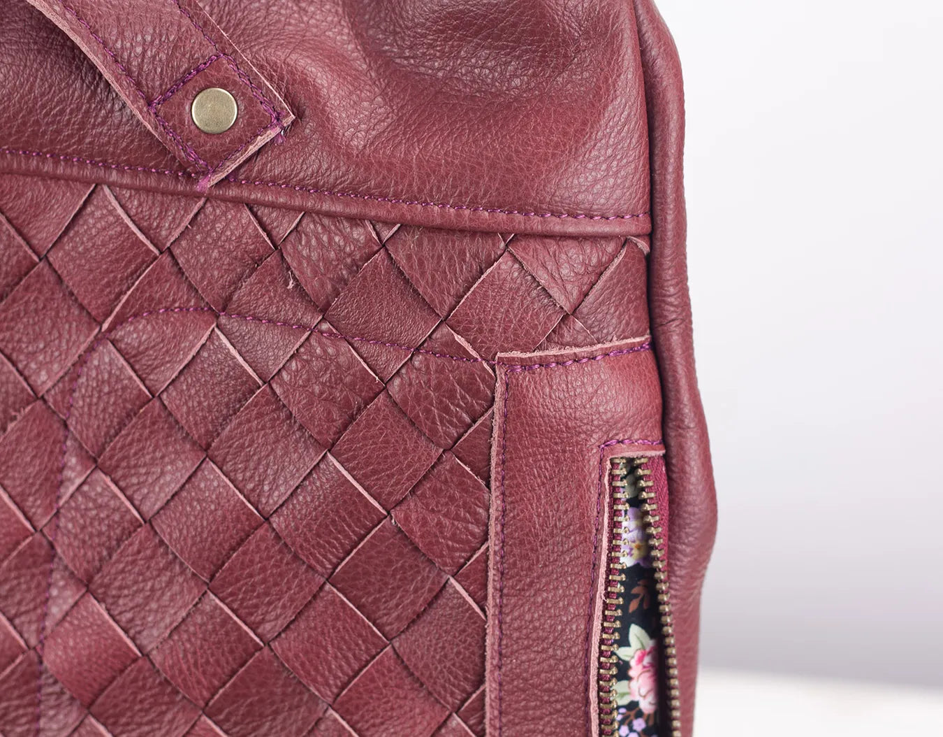 Close-up of a maroon leather bag with woven pattern and zipper detail.
