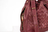 Maroon woven handbag with a gold zipper on a white background